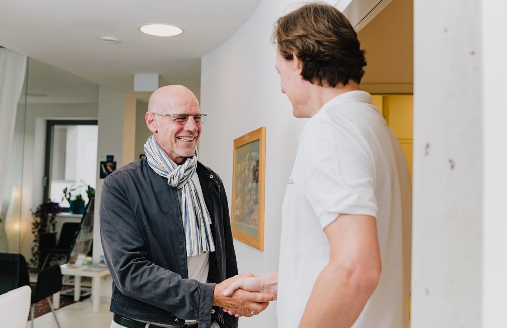 Dr. Kirschbichler begrüßt einen Patienten in der Ordination